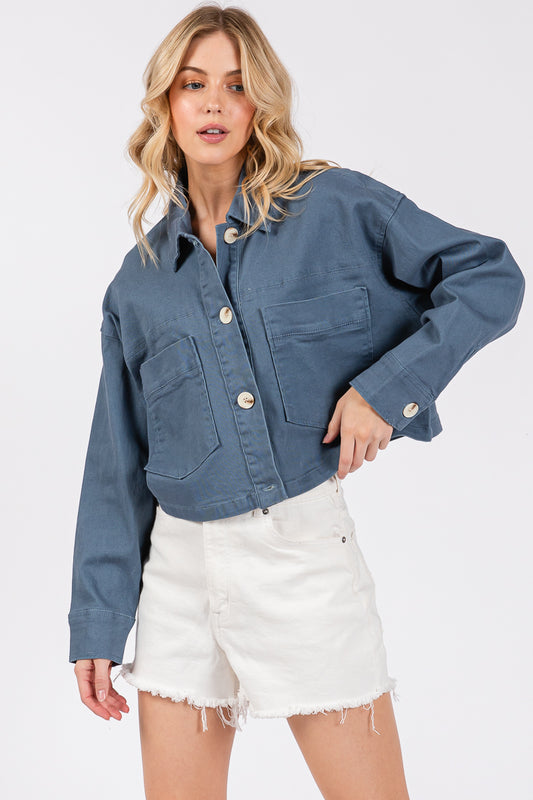 Cropped denim-style jacket with button-down front and oversized buttons, paired with white shorts for a chic look.